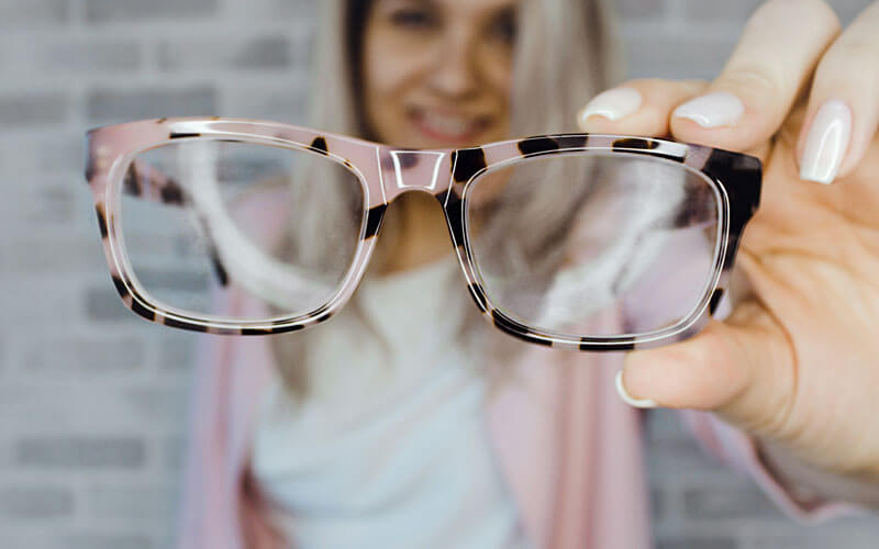 Image of a correct vision patient holding a pair of eye glasses from the Boca Raton Family Eye Care center in West Boca Raton. 